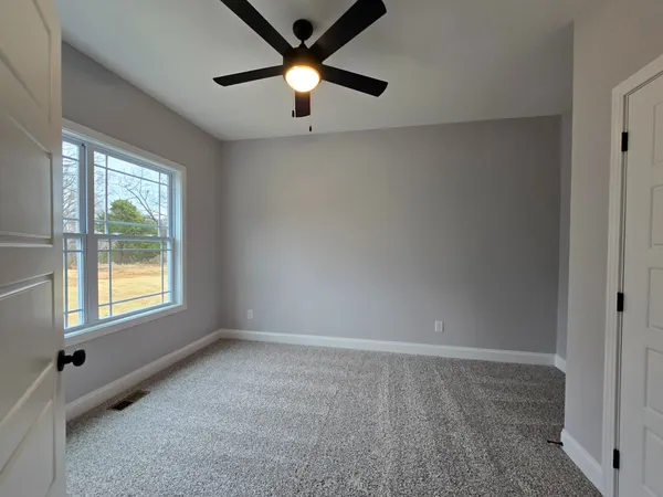 an empty room with a window and a fan