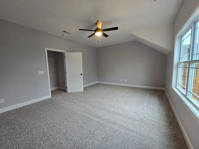 an empty room with windows and fan