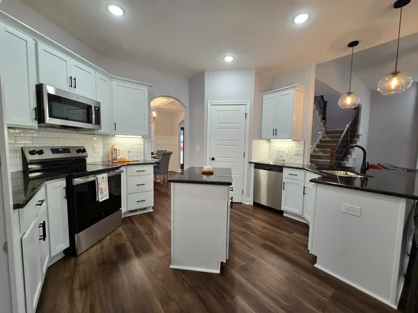 a kitchen with a sink wooden floor and stainless steel appliances
