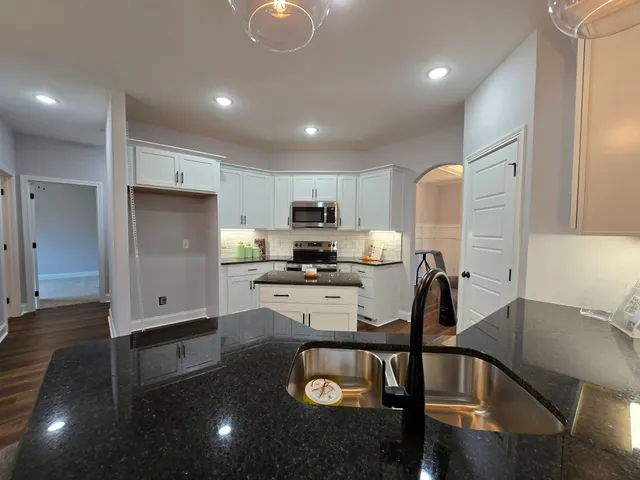 a kitchen with stainless steel appliances granite countertop a refrigerator a sink a stove and cabinets