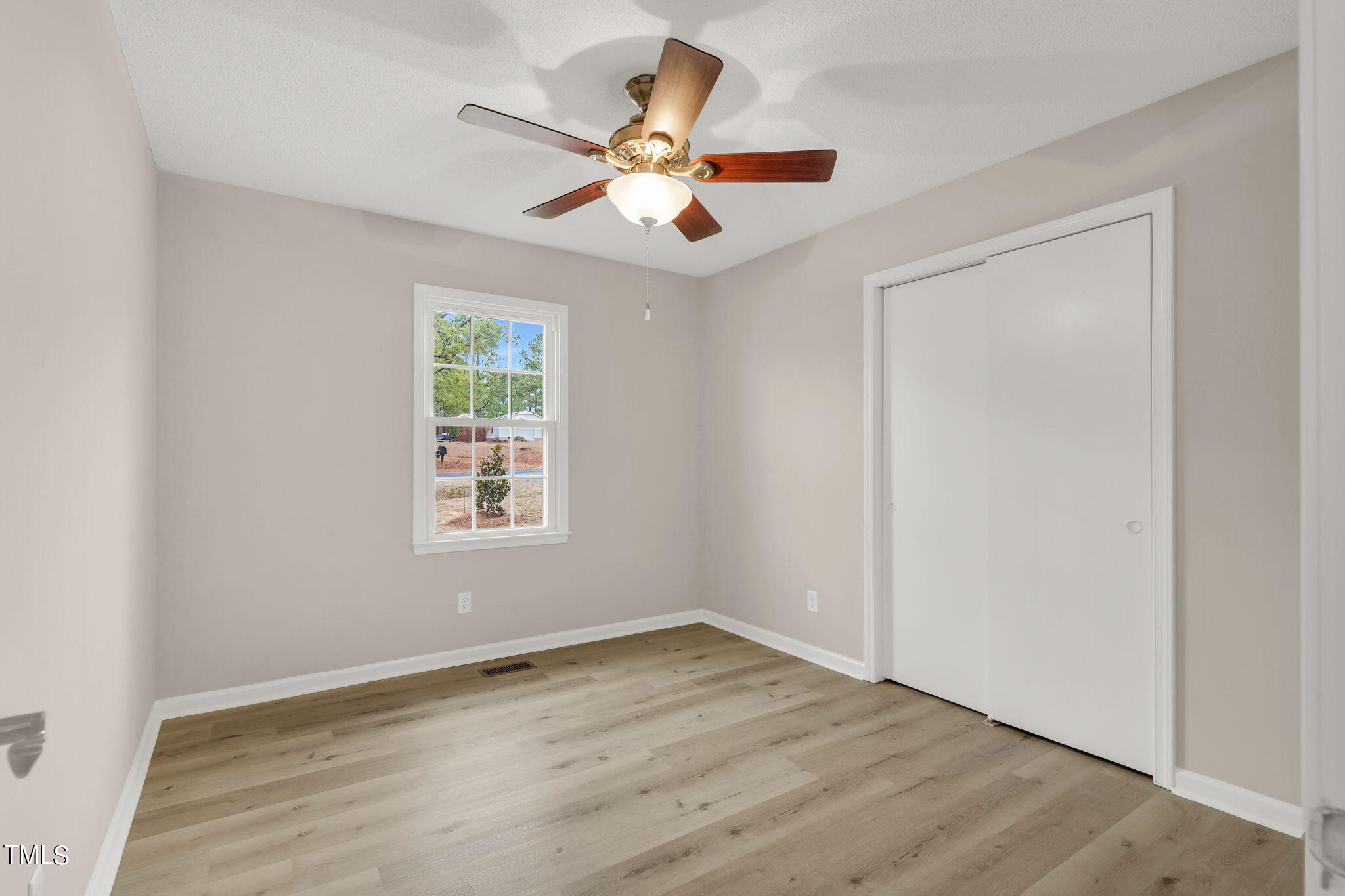 1073 Brick Mill Road Coats, NC 27521 - Photo 15 of 32 an empty room with wooden floor chandelier fan and windows