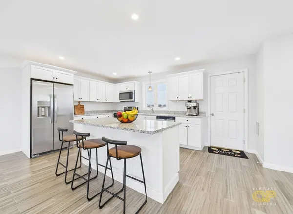 a kitchen with stainless steel appliances a refrigerator a stove a sink dishwasher and white cabinets with wooden floor