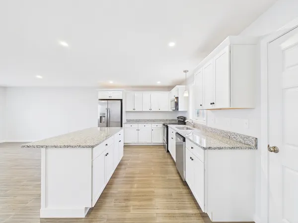 a large kitchen with stainless steel appliances granite countertop a lot of counter space and wooden floor
