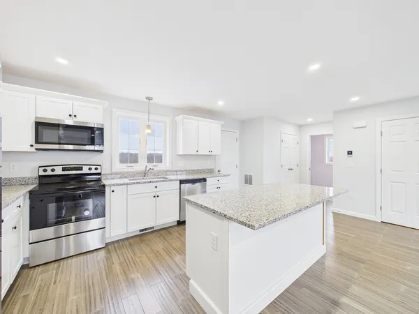 a kitchen with stainless steel appliances granite countertop a stove top oven a sink dishwasher and a refrigerator with wooden floor