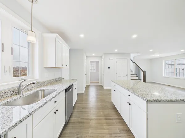 a large kitchen with stainless steel appliances granite countertop a sink dishwasher a stove and white countertops with wooden floor