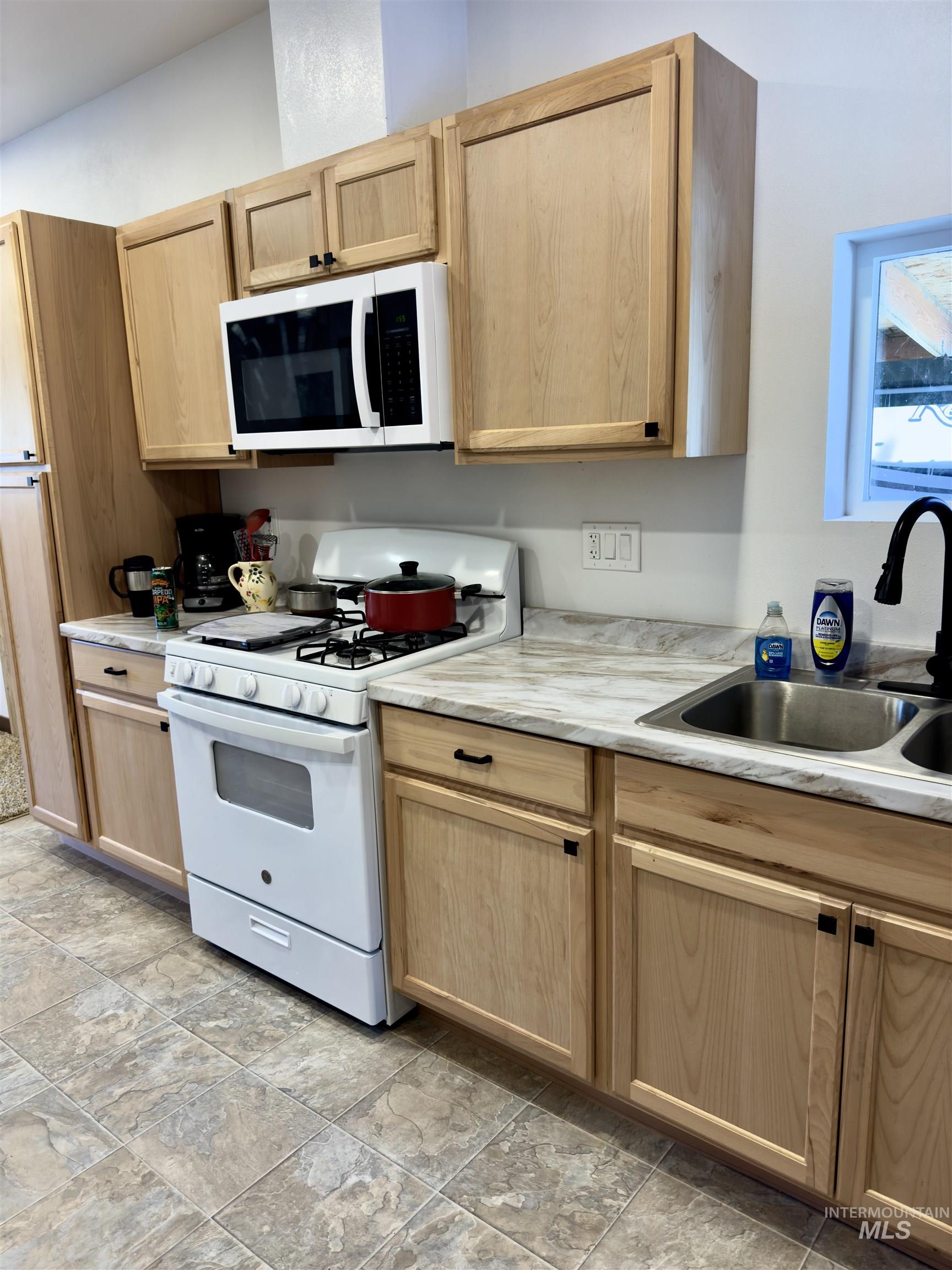 1112 Old Pk Road Deary, ID 83823 - Photo 14 of 23 Kitchen with white appliances, light wood finish cabinets, light countertops, and light stone finish floors