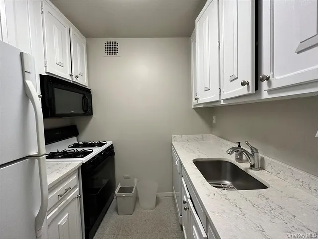 a kitchen with granite countertop a sink a stove and microwave