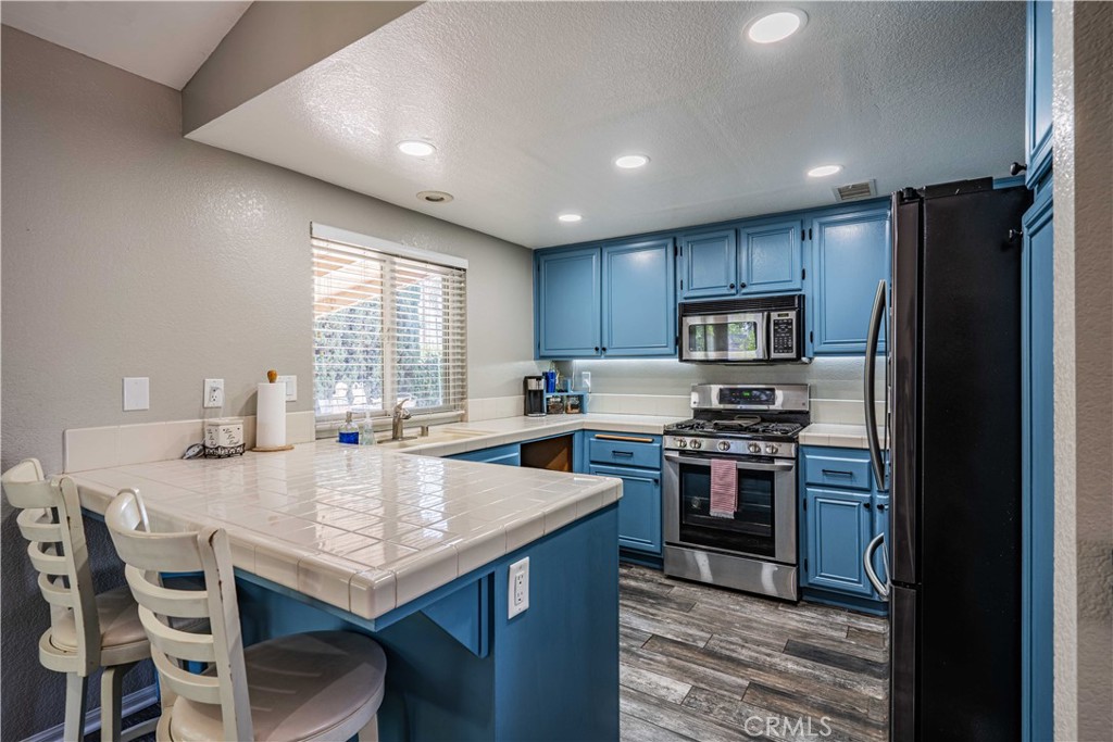 27571 Cabrillo Drive Menifee, CA 92586 - Photo 15 of 56 a kitchen with stainless steel appliances granite countertop a stove a refrigerator a sink a dining table and chairs