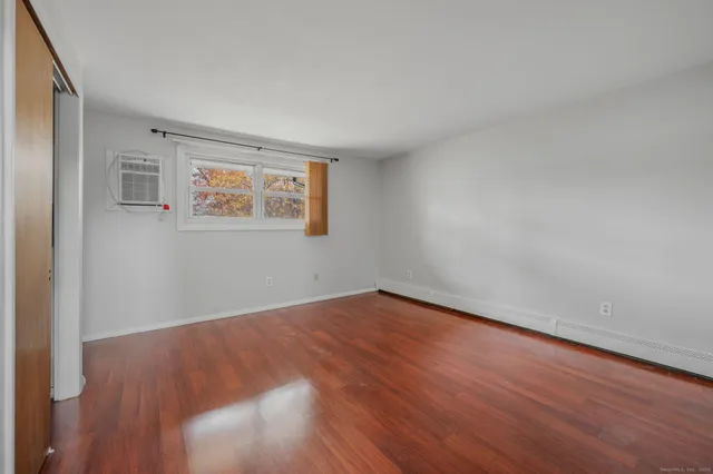 a view of an empty room with wooden floor and a window