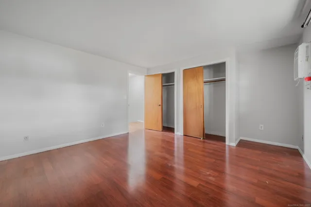 a view of an empty room with wooden floor and closet