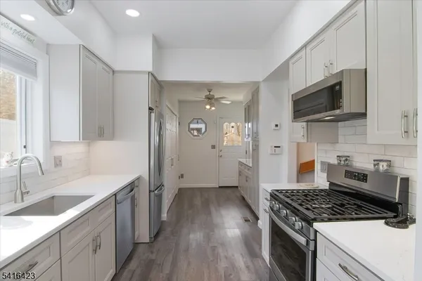 a kitchen with stainless steel appliances a sink dishwasher a stove and a microwave oven with cabinets