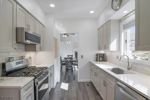 a kitchen with stainless steel appliances a sink dishwasher a stove top oven a refrigerator with wooden floor and cabinets