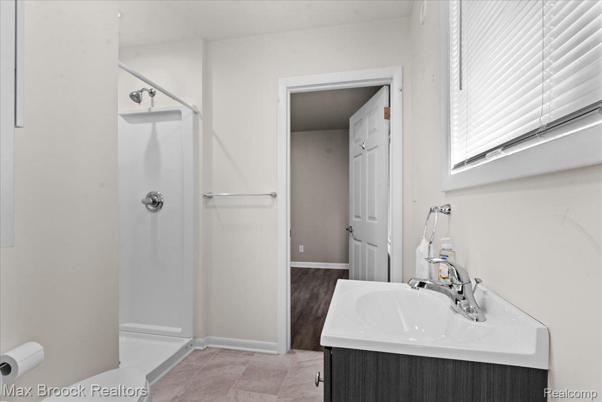 513 West 9 Mile Road, Unit 1 Hazel Park, MI 48030 - Photo 13 of 21 Full Bathroom featuring a shower stall, a single vanity with an integrated sink, and window blinds