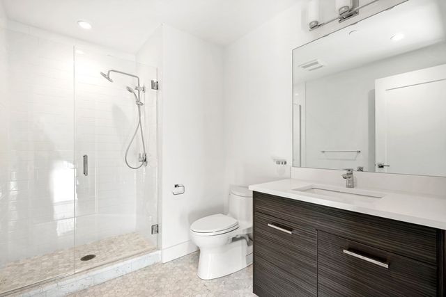 a bathroom with a shower sink vanity mirror and toilet
