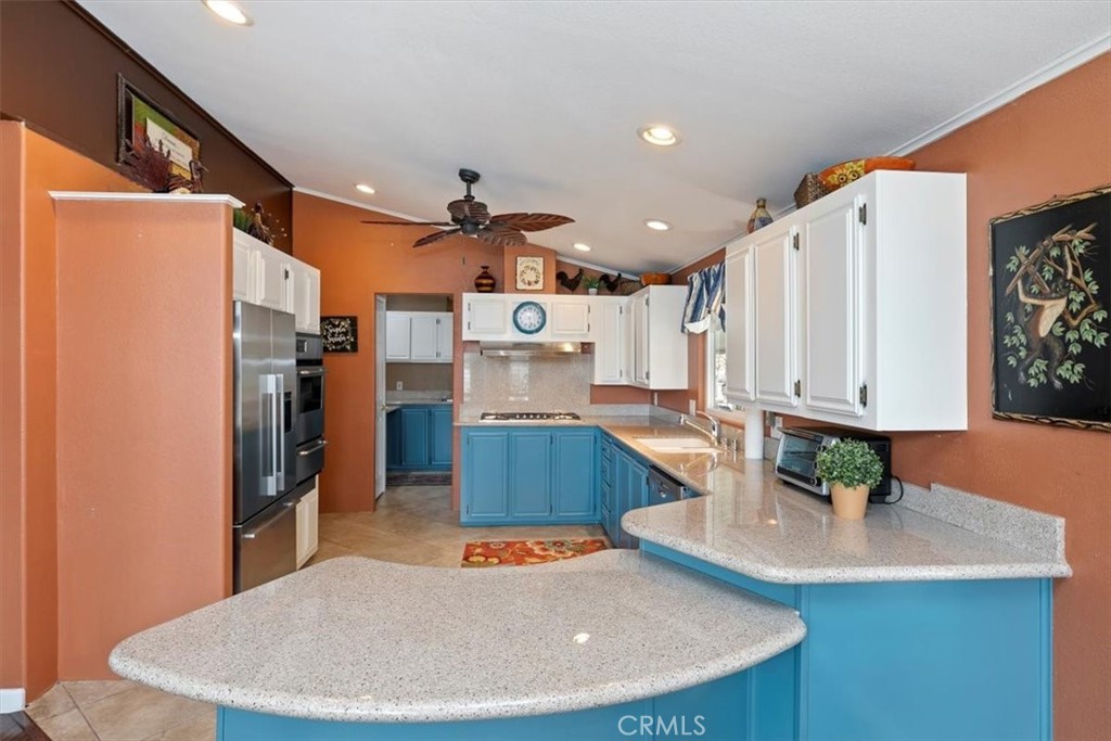 46618 Madison Street, Unit 85 Indio, CA 92201 - Photo 30 of 50 a kitchen with stainless steel appliances kitchen island granite countertop a table chairs in it and wooden floors