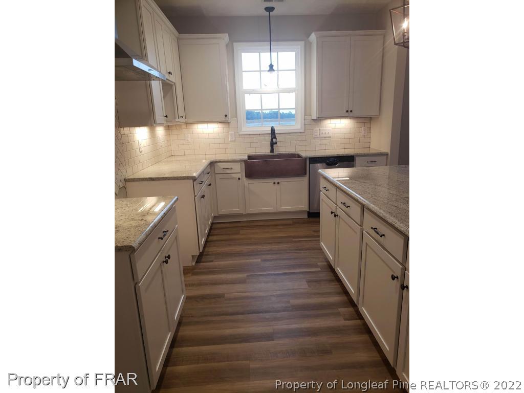 2945 Hayfield Road Wade, NC 28395 - Photo 17 of 26 a large kitchen with granite countertop a sink and dishwasher a stove top oven with wooden floor