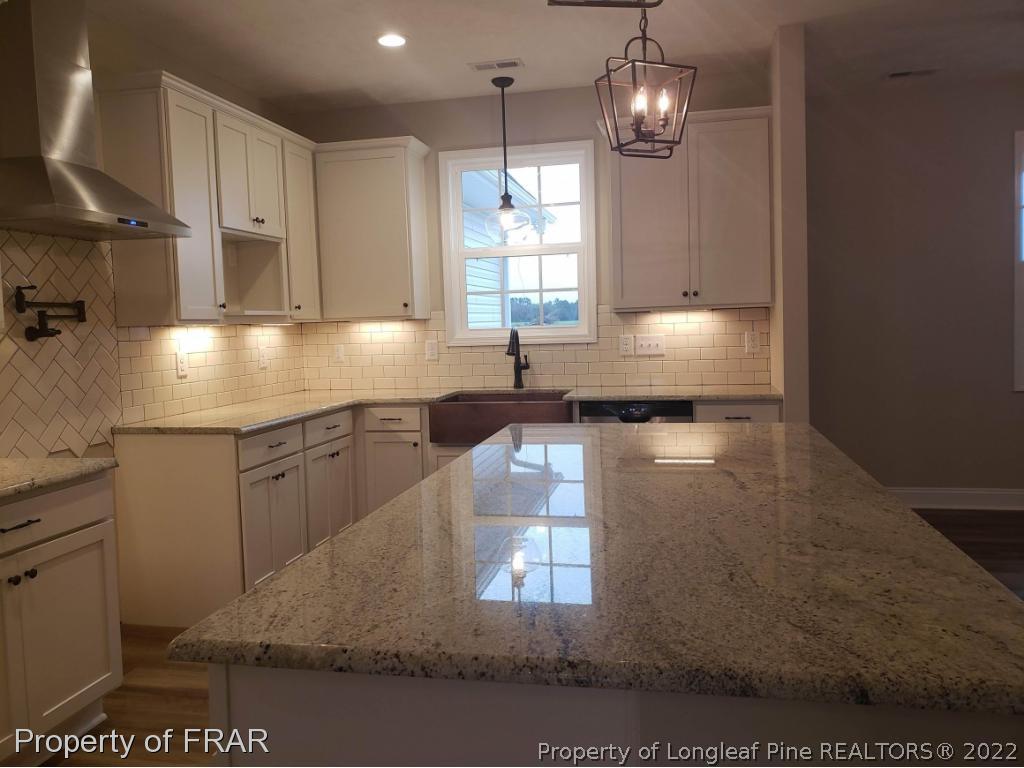 2945 Hayfield Road Wade, NC 28395 - Photo 18 of 26 a kitchen with kitchen island granite countertop a sink stainless steel appliances and cabinets