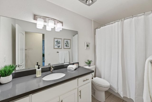 a bathroom with a granite countertop sink and a mirror with toilet