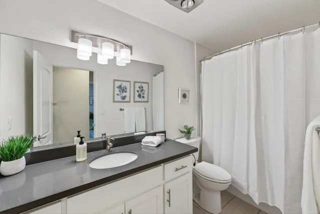 a bathroom with a granite countertop sink and a mirror with toilet