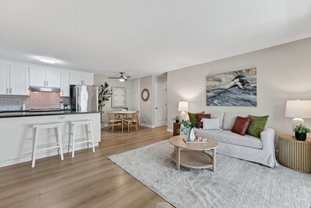 a living room with furniture a wooden floor and kitchen view