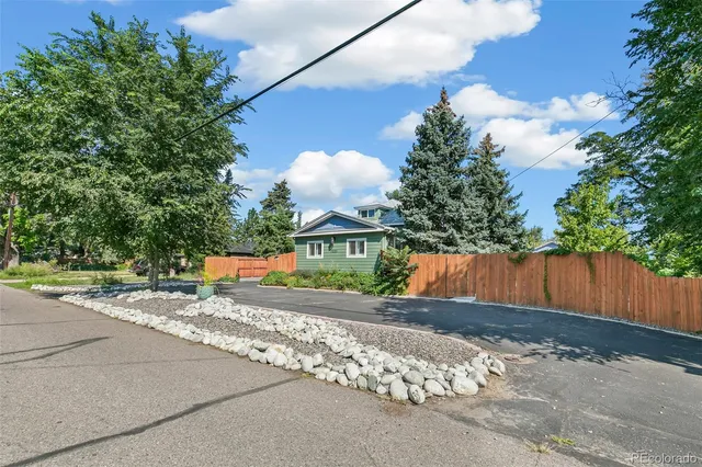 a view of a house with a small yard and large tree