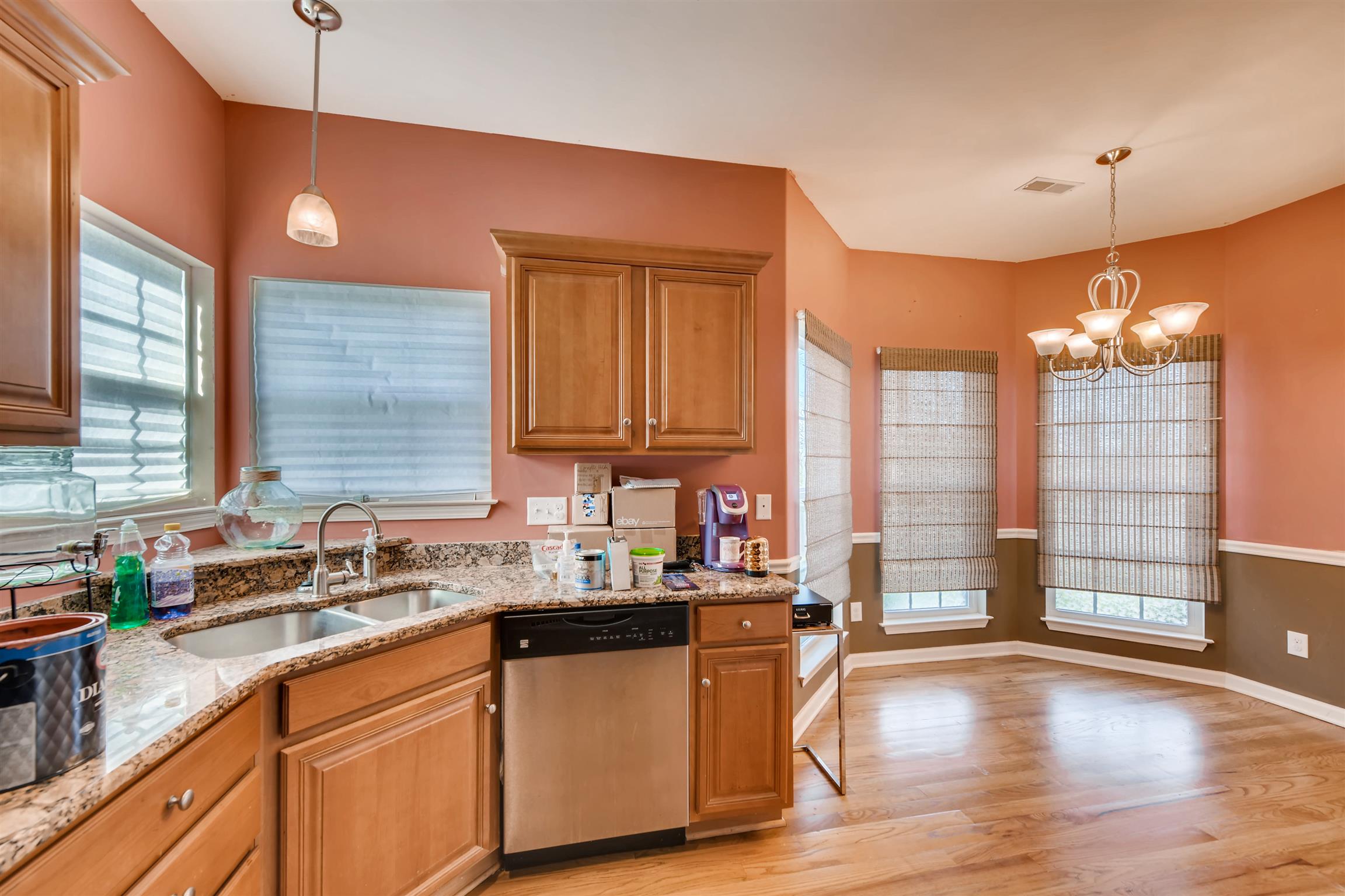 1054 Golf View Way Spring Hill, TN 37174 - Photo 8 of 16 a kitchen with stainless steel appliances granite countertop a sink dishwasher a stove a dining table and chairs with wooden floor