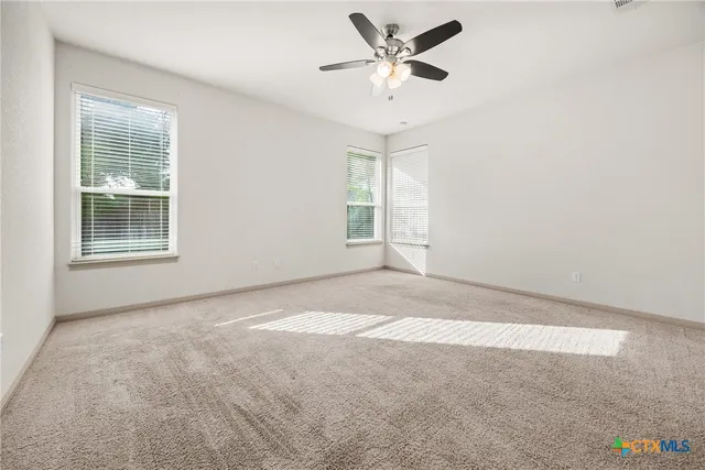 an empty room with windows and ceiling fan
