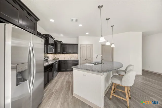 a kitchen with a sink stainless steel appliances and wooden floor