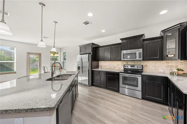 a kitchen with stainless steel appliances granite countertop a sink stove microwave and refrigerator