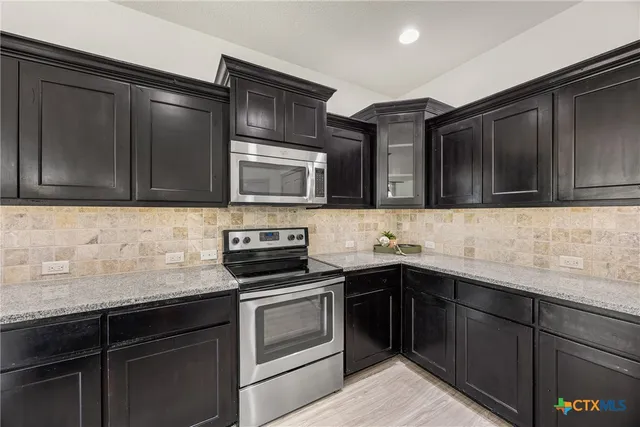 a kitchen with stainless steel appliances granite countertop a sink stove and microwave