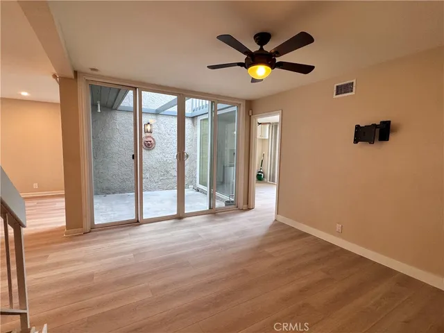 a view of an empty room with wooden floor a ceiling fan