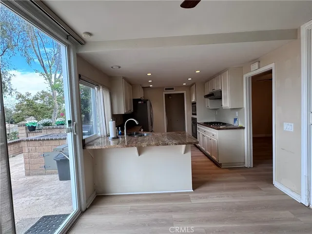 a kitchen with stainless steel appliances granite countertop a refrigerator a sink a stove and a wooden floors