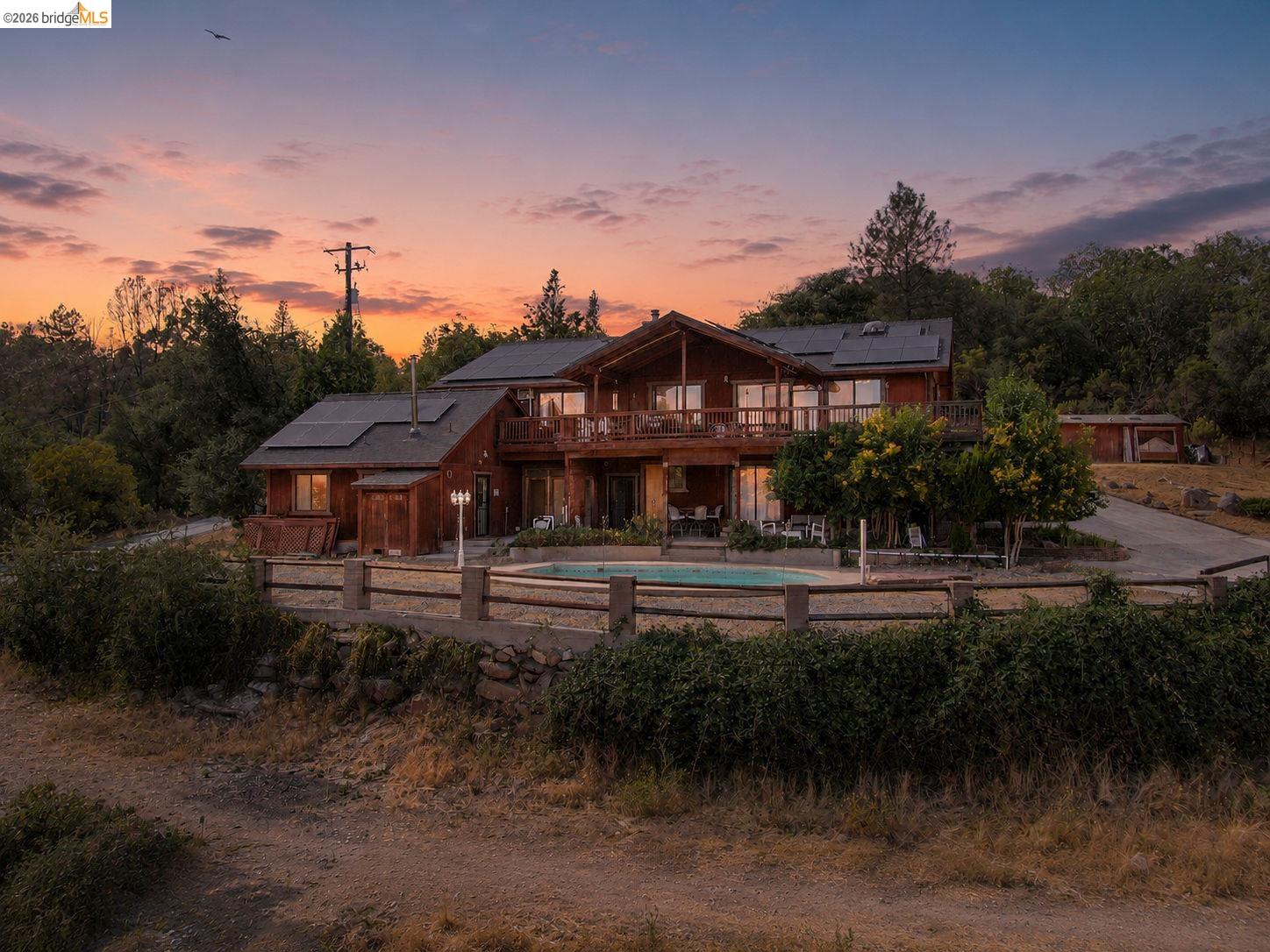 22963 Robertson Ranch Road Sonora, CA 95370 - Photo 76 of 90 Expansive wood-sided residence featuring multiple outdoor decks, a ground-level swimming pool, and an asphalt driveway