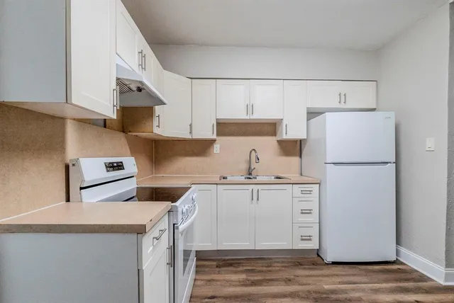 a kitchen with cabinets appliances and wooden floor
