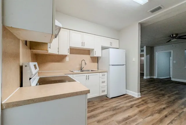 a kitchen with a stove a refrigerator and white cabinets