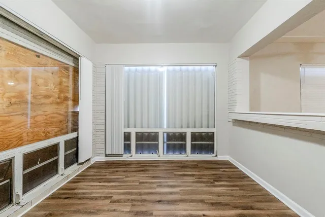 a view of an empty room with wooden floor and a window