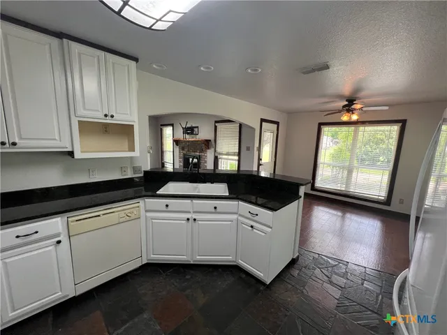 a kitchen with kitchen island wooden floors appliances and a counter top space