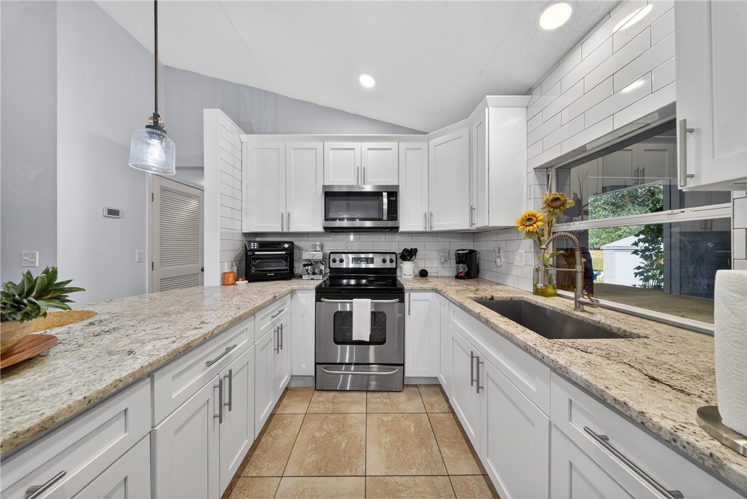 5809 Seagrape Drive Fort Pierce, FL 34982 - Photo 13 of 35 a large kitchen with granite countertop a sink and a stove top oven