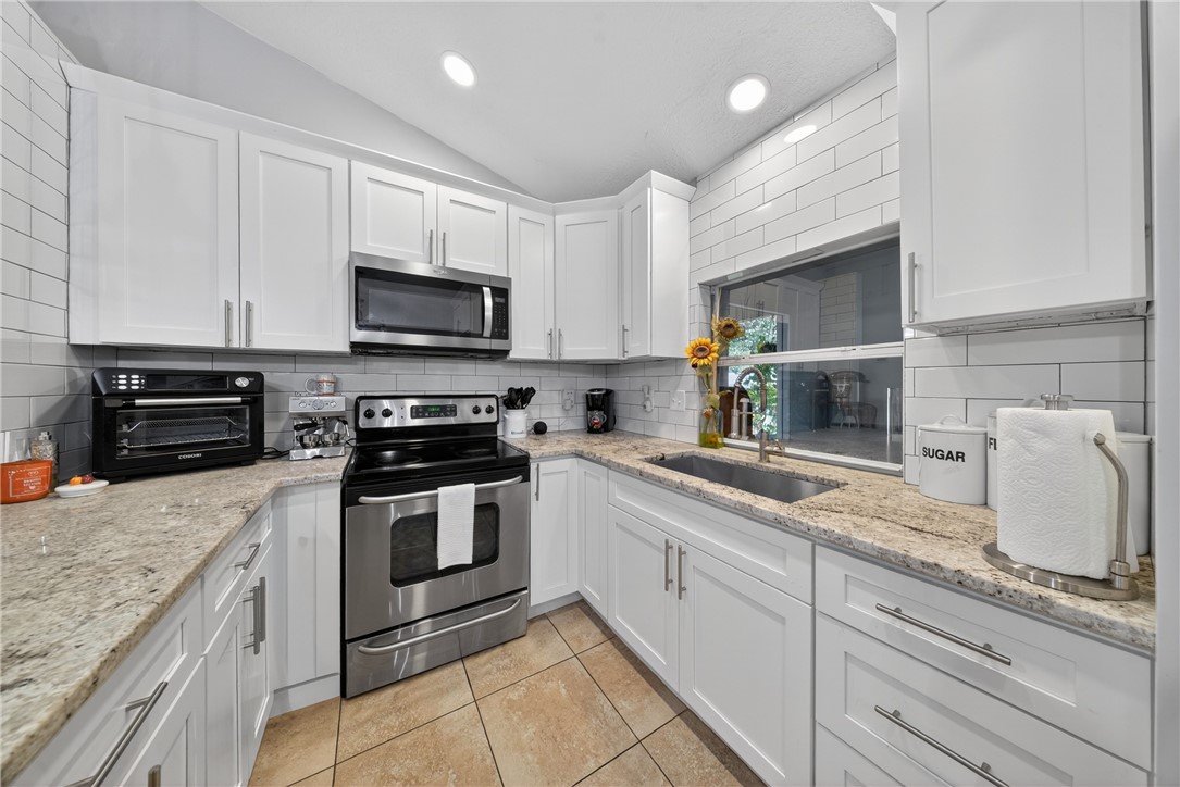5809 Seagrape Drive Fort Pierce, FL 34982 - Photo 14 of 35 a kitchen with granite countertop a sink stainless steel appliances and cabinets