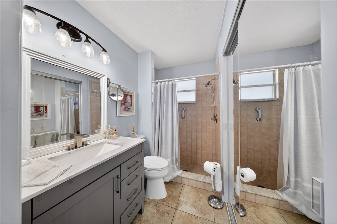 5809 Seagrape Drive Fort Pierce, FL 34982 - Photo 18 of 35 a spacious bathroom with a granite countertop sink toilet a large mirror a shower and a