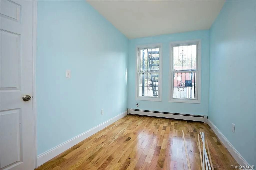 577 Logan Street Brooklyn, NY 11208 - Photo 6 of 8 a view of empty room with wooden floor and fan