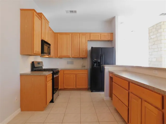 a large kitchen with stainless steel appliances granite countertop a sink and cabinets