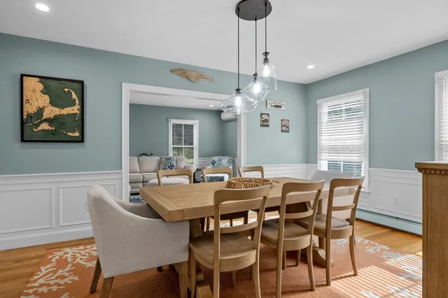 a open kitchen with a refrigerator a sink dishwasher a dining table and chairs with wooden floor