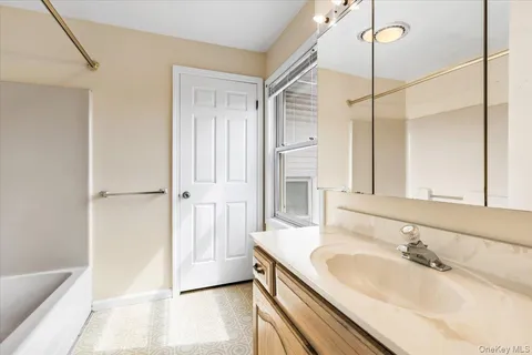 a bathroom with a granite countertop sink a mirror and a bathtub