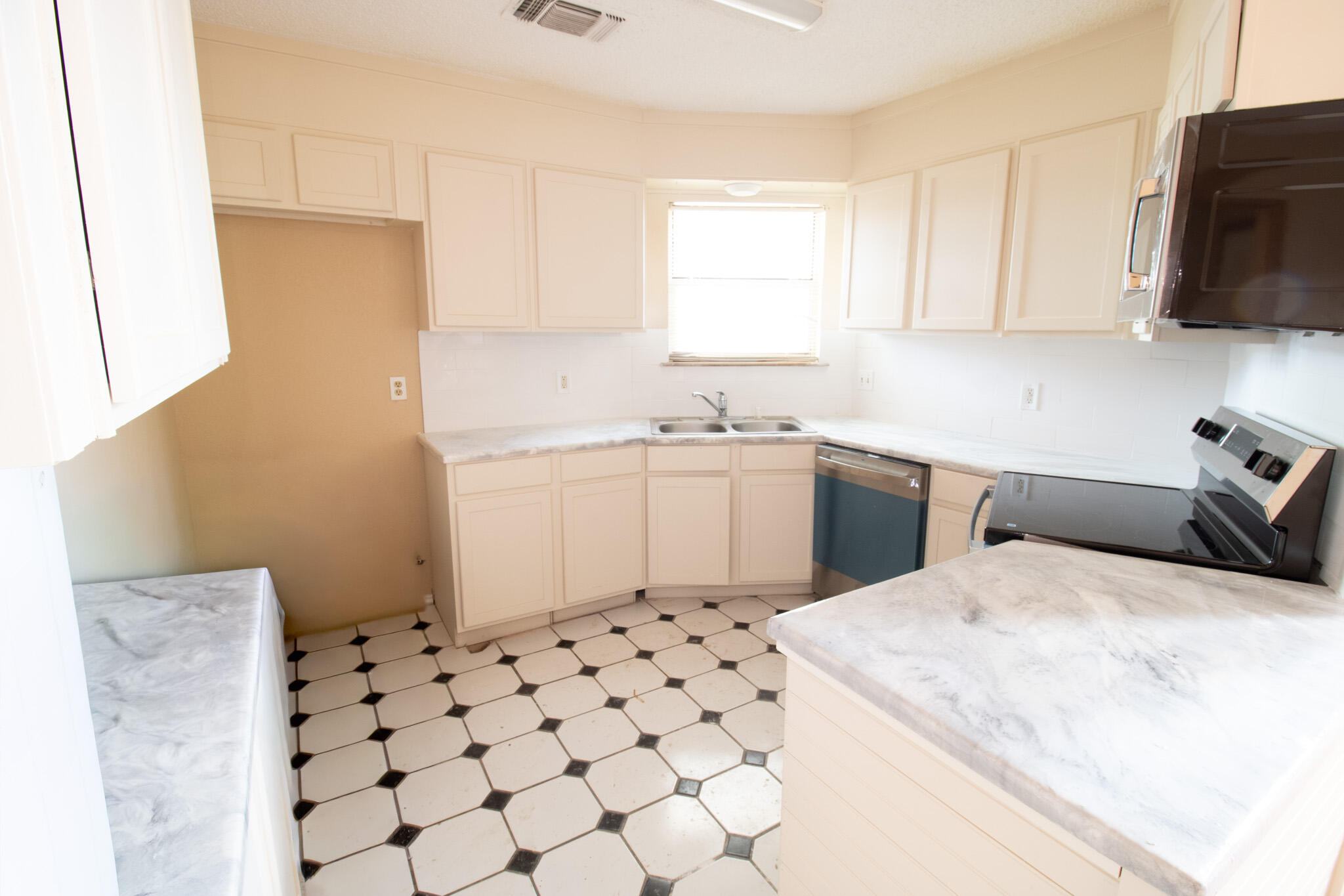 2202 93rd Place Lubbock, TX 79423 - Photo 4 of 11 a kitchen with a sink a stove top oven and white cabinets