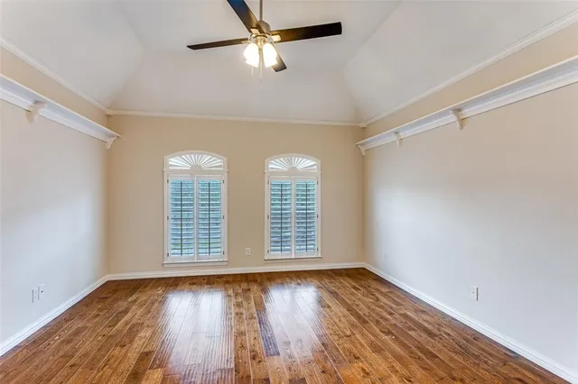 an empty room with wooden floor chandelier fan and windows