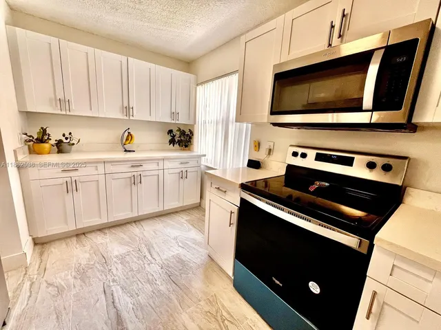 a kitchen with a refrigerator a microwave a sink and cabinets