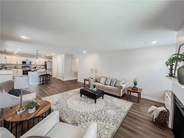 a kitchen with stainless steel appliances granite countertop a stove top oven a refrigerator a sink dishwasher a dining table and chairs with wooden floor