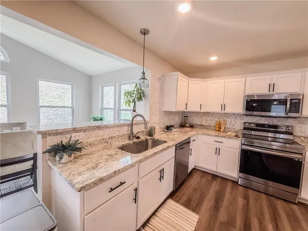 a kitchen with white cabinets and sink