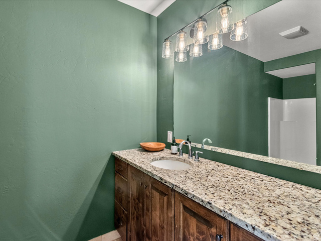 1225 Old Oregon Road Soda Springs, ID 83276 - Photo 21 of 67 Spacious vanity featuring a light-toned countertop with an undermount sink, dark wood-finish cabinetry, and a large mirror with multi-bulb lighting